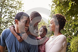 Young African American parents carrying children in garden