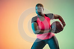 Young african-american plus size female model`s training on gradient background