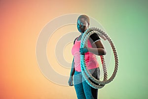 Young african-american plus size female model`s training on gradient background