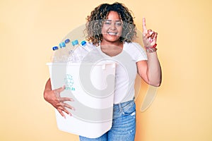 Young african american plus size woman holding recycling wastebasket with plastic bottles surprised with an idea or question