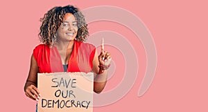 Young african american plus size woman holding save our democracy banner surprised with an idea or question pointing finger with