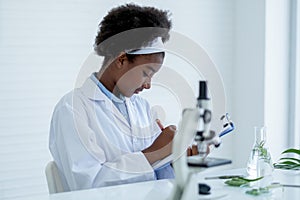 Young African American Scientist record analysis data and sit in room with other tools in laboratory and experiment with plant