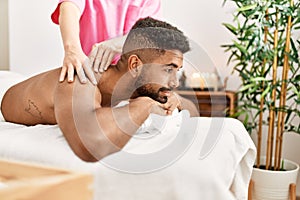 Young african american smiling happy reciving back massage at beauty center