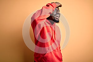 Young african american sporty man wearing sweatshirt with hoodie over yellow background very happy and smiling looking far away