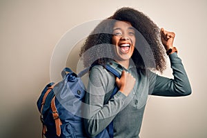 Young african american student woman with afro hair wearing backpack over background screaming proud and celebrating victory and