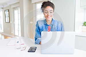 Young african american student woman using computer laptop with a happy face standing and smiling with a confident smile showing