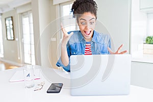 Young african american student woman using computer laptop very happy and excited, winner expression celebrating victory screaming