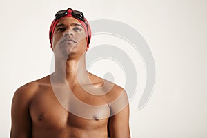 Young African American swimmer in red cap and black goggles looking up