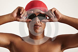 Young African American swimmer in red cap putting on black goggles