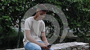 Young african american teenager boy using mobile phone while relaxing outdoor