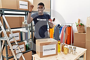 Young african american volunteer man packing donations box for charity angry and mad raising fist frustrated and furious while