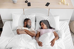 Young african american wife and husband sleeping together on comfortable bed with soft pillow, white blanket
