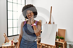 Young african american woman with afro hair at art studio touching mouth with hand with painful expression because of toothache or