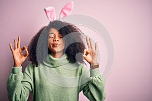 Young african american woman with afro hair wearing easter rabbit ears costume over pink background relax and smiling with eyes