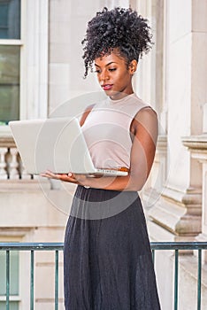 Young African American woman with afro hairstyle wearing sleeveless light color top, black skirt, standing in vintage office