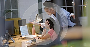 Young African American woman assists a biracial woman in a business office setting