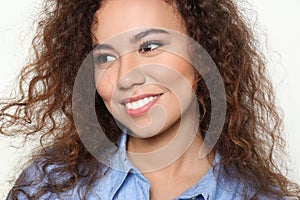 Young African-American woman with beautiful face on light background