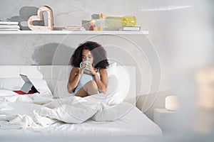 Woman Drinking Coffee Watching Movie In Bed on Sunday