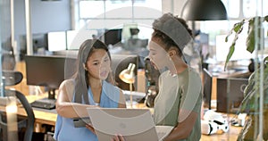 Young African American woman and biracial woman collaborate in a business office