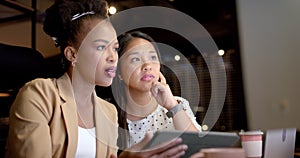 Young African American woman and biracial woman collaborate in a business office