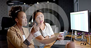 Young African American woman and biracial woman discuss business work in an office