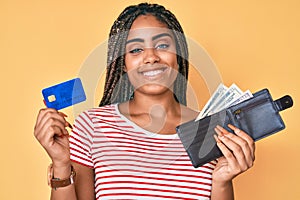 Young african american woman with braids holding wallet with dollars and credit card smiling with a happy and cool smile on face