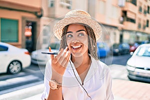 Young african american woman with braids smiling happy sending voice message on the phone outdoors on a sunny day of summer