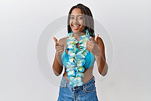 Young african american woman with braids wearing bikini and hawaiian lei pointing fingers to camera with happy and funny face