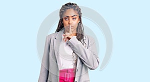 Young african american woman with braids wearing business clothes asking to be quiet with finger on lips