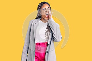 Young african american woman with braids wearing business clothes shouting and screaming loud to side with hand on mouth