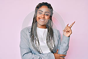 Young african american woman with braids wearing business jacket smiling happy pointing with hand and finger to the side