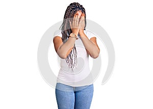 Young african american woman with braids wearing casual clothes with sad expression covering face with hands while crying