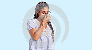 Young african american woman with braids wearing casual summer clothes and glasses tired rubbing nose and eyes feeling fatigue and