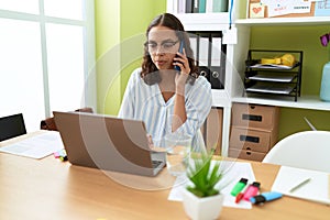 Young african american woman business worker using laptop talking on smartphone at office