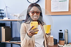 Young african american woman business worker using smartphone drinking coffee at office