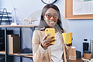 Young african american woman business worker using smartphone drinking coffee at office