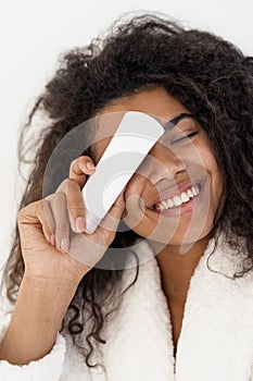 Young african american woman cover eye with cosmetics cream