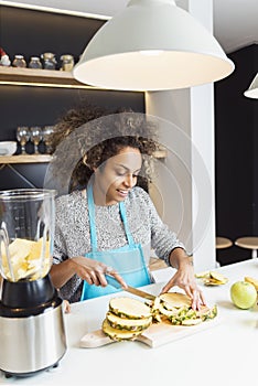 Young African American woman cutting fruit in the kitchen