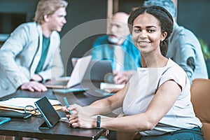 Young African American woman at desk within multi-ethnic business team. Group comprises freelancers and programmers who