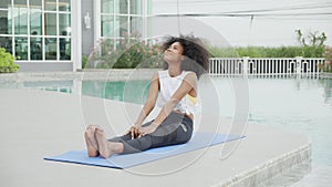 Young African American woman doing exercise with stretch muscles lag in the poolside.