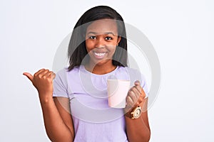 Young african american woman drinking a cup of coffee over isolated background pointing and showing with thumb up to the side with