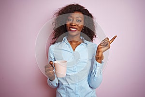 Young african american woman drinking cup of coffee over isolated pink background very happy pointing with hand and finger to the