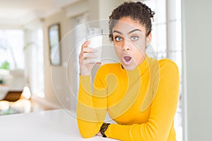 Young african american woman drinking a glass of fresh milk scared in shock with a surprise face, afraid and excited with fear