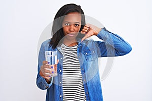 Young african american woman drinking a glass of fresh water over isolated background with angry face, negative sign showing