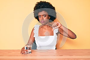 Young african american woman drinking glass of water with angry face, negative sign showing dislike with thumbs down, rejection