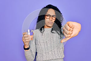 Young african american woman drinking glass of water over isolated purple background with angry face, negative sign showing