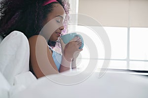 Black Woman Drinking Coffee In Bed Smiling