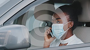 Young african american woman ethnic black girl afro lady driver wearing medical protective face mask sitting in car