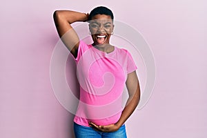 Young african american woman expecting a baby, touching pregnant belly crazy and scared with hands on head, afraid and surprised