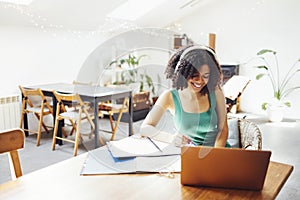 Young African American woman in haedphones is working on a laptop